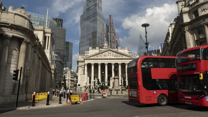 Buses pass in the City of London financial district outside the Royal Exchange near the Bank of England on 2nd July 2021 in London, United Kingdom.