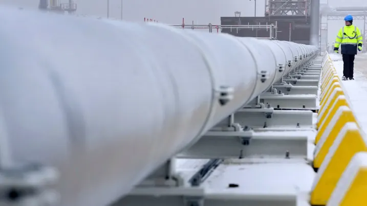 A worker walks past gas pipes that connect the Floating Storage and Regasification Unit (FSRU) ship 'Hoegh Esperanza' with the main land, during the opening ceremony of the Uniper Liquefied Natural Gas (LNG) terminal at the Jade Bight in Wilhelmshaven, northern Germany on December 17, 2022. - Germany will on December 17 inaugurate its first liquefied natural gas (LNG) terminal, built in record time, as the country scrambles to adapt to life without Russian energy. (Photo by Michael Sohn / POOL / AFP) (Photo