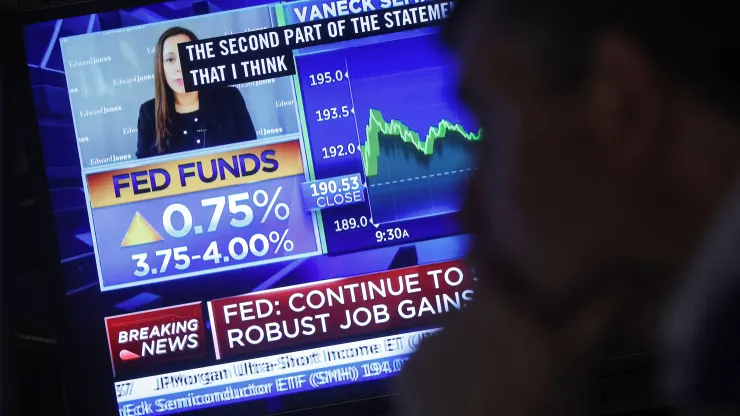 A screen displays the Fed rate announcement as a trader works on the floor of the New York Stock Exchange (NYSE), November 2, 2022.