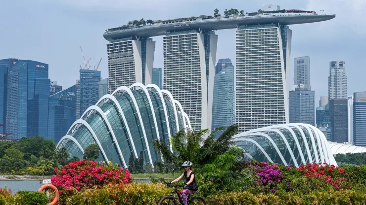 A woman rides her bicycle with the Marina Bay Sands hotel and high rise buildings in the background in Singapore on September 4, 2023.