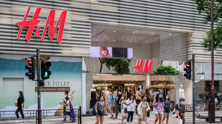 HONG KONG, CHINA - 2021/08/07: Pedestrians cross the street in front of the Swedish multinational clothing design retail company Hennes & Mauritz, H&M, store in Hong Kong. (Photo by Budrul Chukrut/SOPA Images/LightRocket via Getty Images)